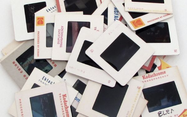 Scattered stack of photo slides and negatives on a white surface