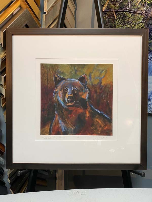 Framed colorful painting of a bear on a display easel