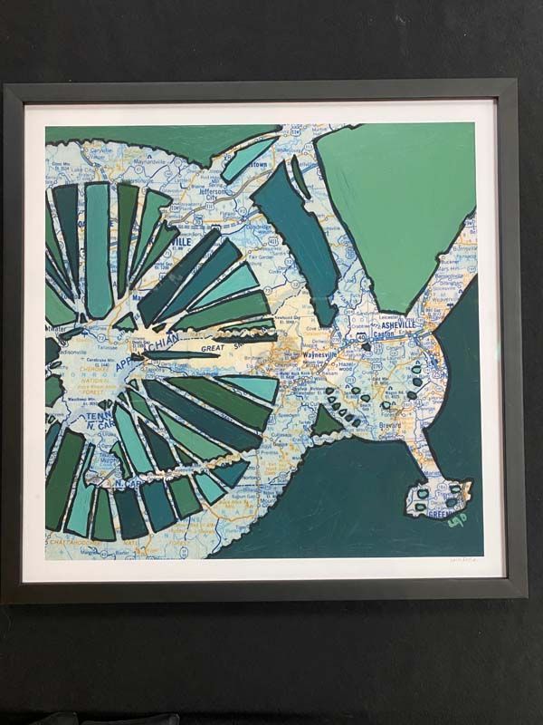 Framed mosaic artwork of a bicycle wheel and handlebars in teal, white, and green tones
