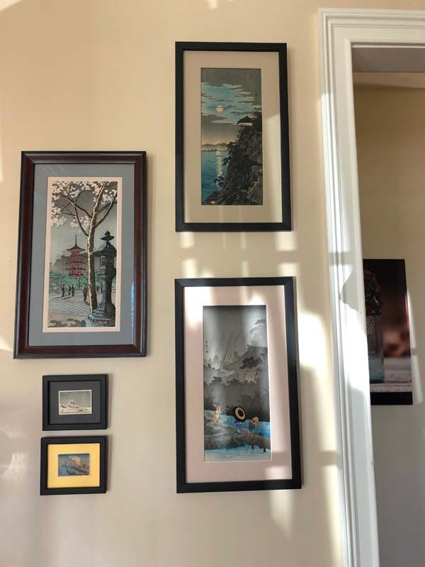 Wall with five framed art prints in black frames, including a tree scene and abstract designs.