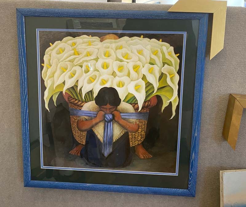Framed painting of a child with head bowed before a large bouquet of white calla lilies and blue flowers