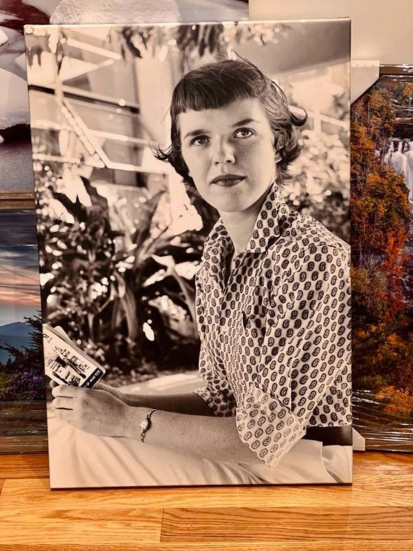 Black-and-white portrait of a seated person holding a book, wearing a patterned blouse.