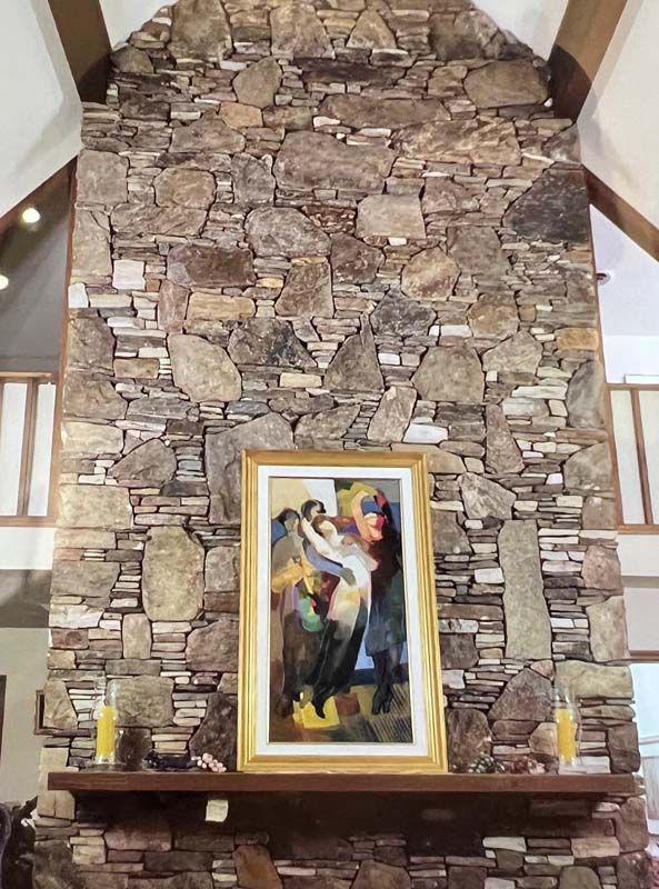 Stone fireplace with a framed colorful painting on the mantel