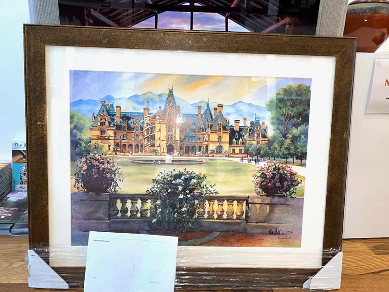 Framed painting of a grand historic building with gardens and a balcony railing in the foreground