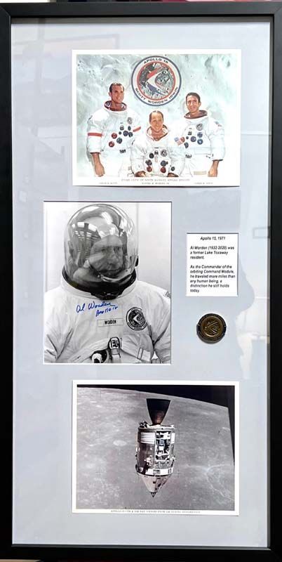 Framed NASA astronaut memorabilia with three photos and mission patches on a gray display background