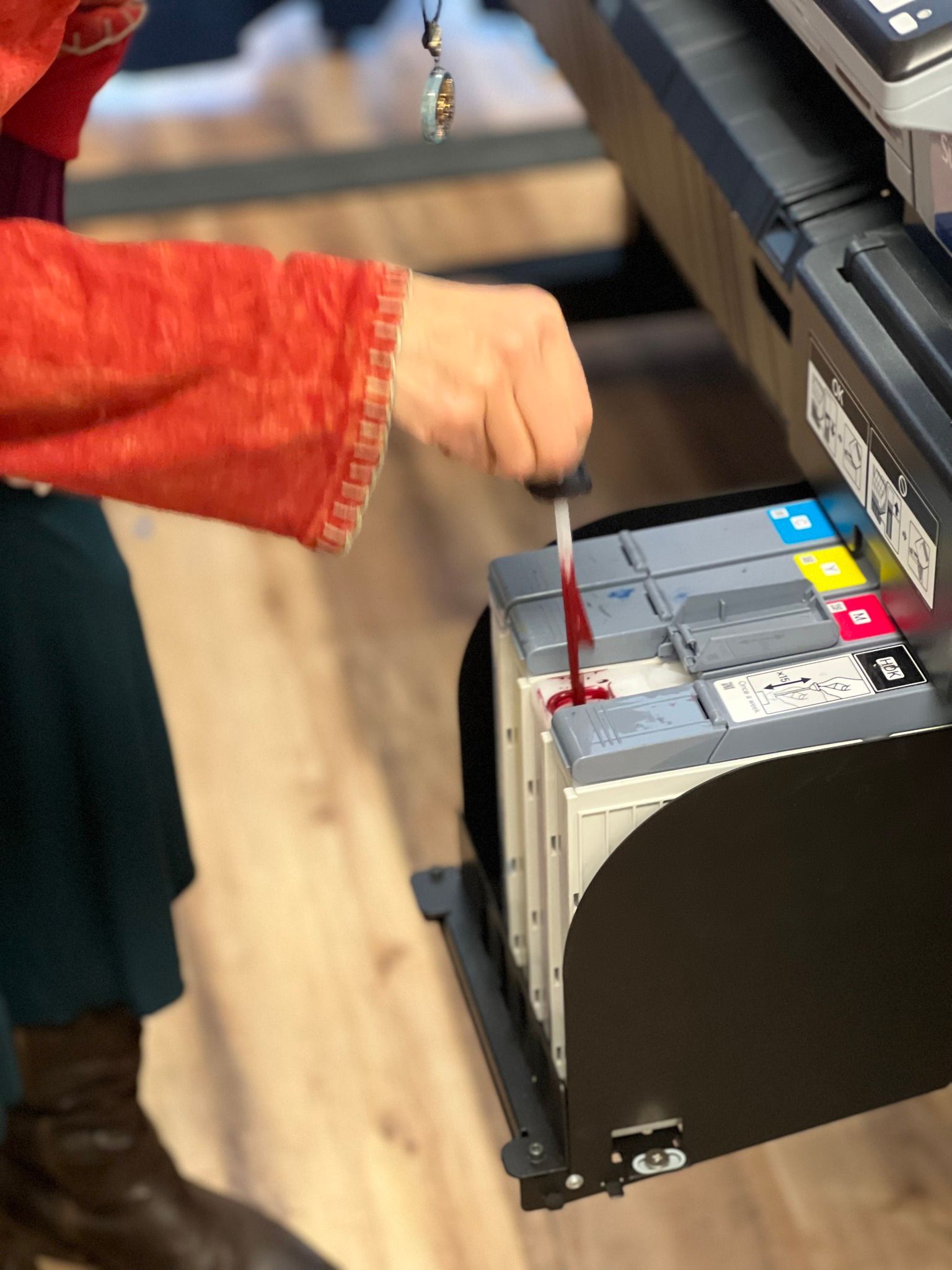 Person inserting a red paper form into a ballot-counting machine
