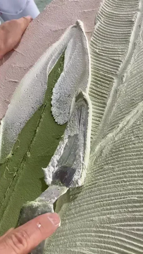 Close-up of a torn green leaf held by fingers, showing white inner fibers and damaged edges