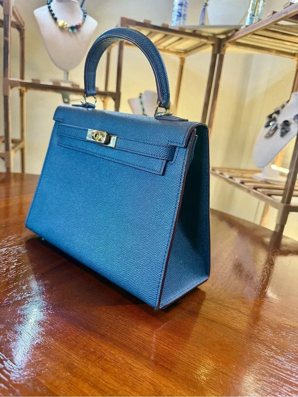 Blue textured handbag on a wooden table in a jewelry store display