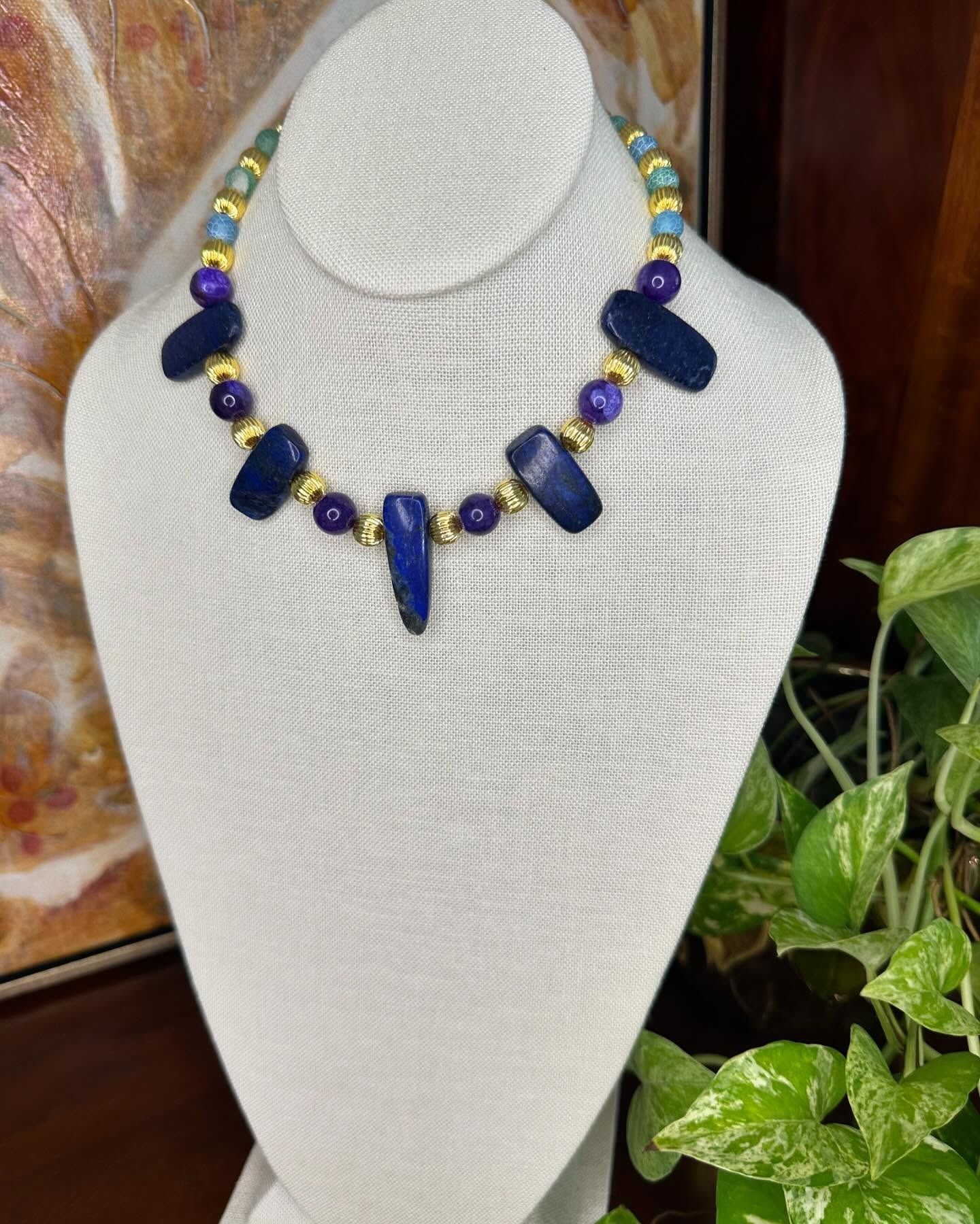White necklace display bust with a blue and yellow beaded necklace featuring large blue stone pendants