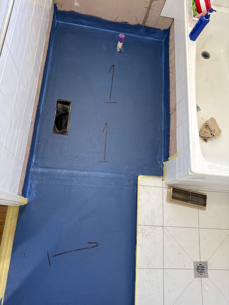 Blue floor in a small room with a drain, wall corner, and a few scattered items. Blue floor in a small room with a drain, wall corner, and a few scattered items.