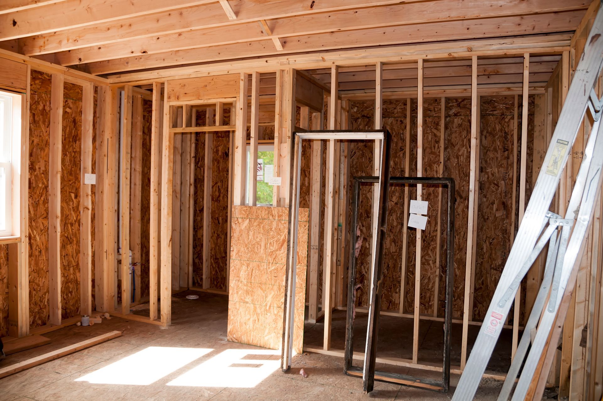 Interior of a house under construction; wooden frame walls, door frames, and window.