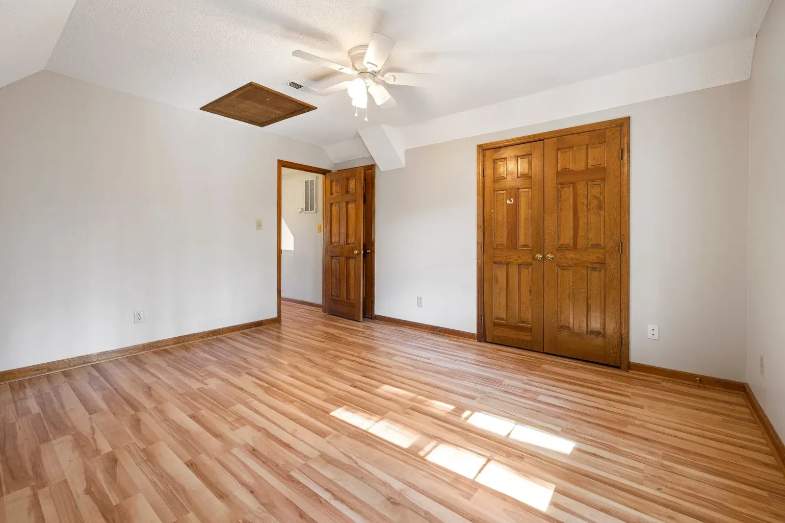 An empty room with hardwood floors and a ceiling fan.