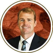 Portrait of a smiling person in a suit and tie against a red textured background