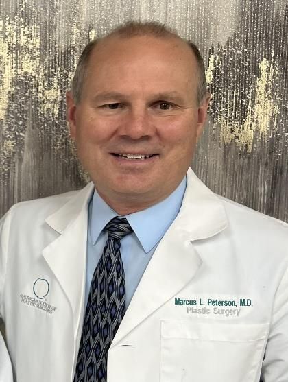 Portrait of a smiling doctor in a white lab coat and tie against a textured gray background