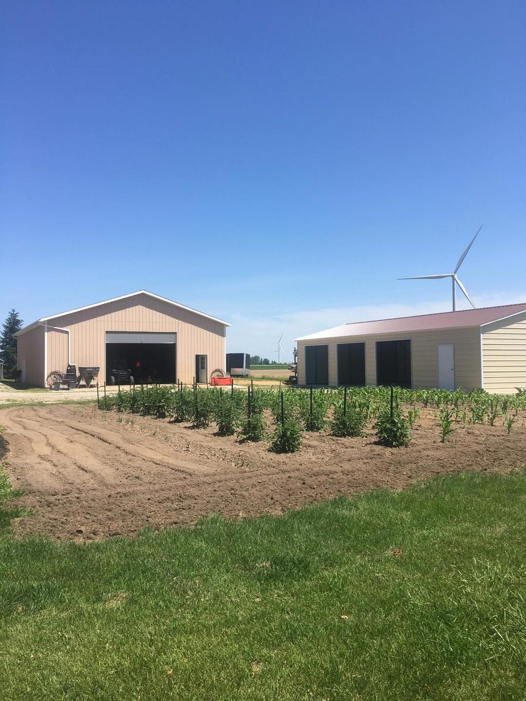 A farm with a lot of buildings and a windmill in the background