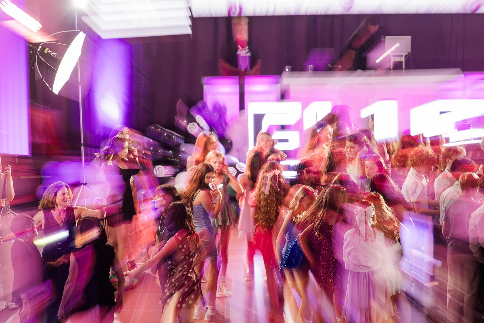 Party scene with blurred figures dancing under purple lights.