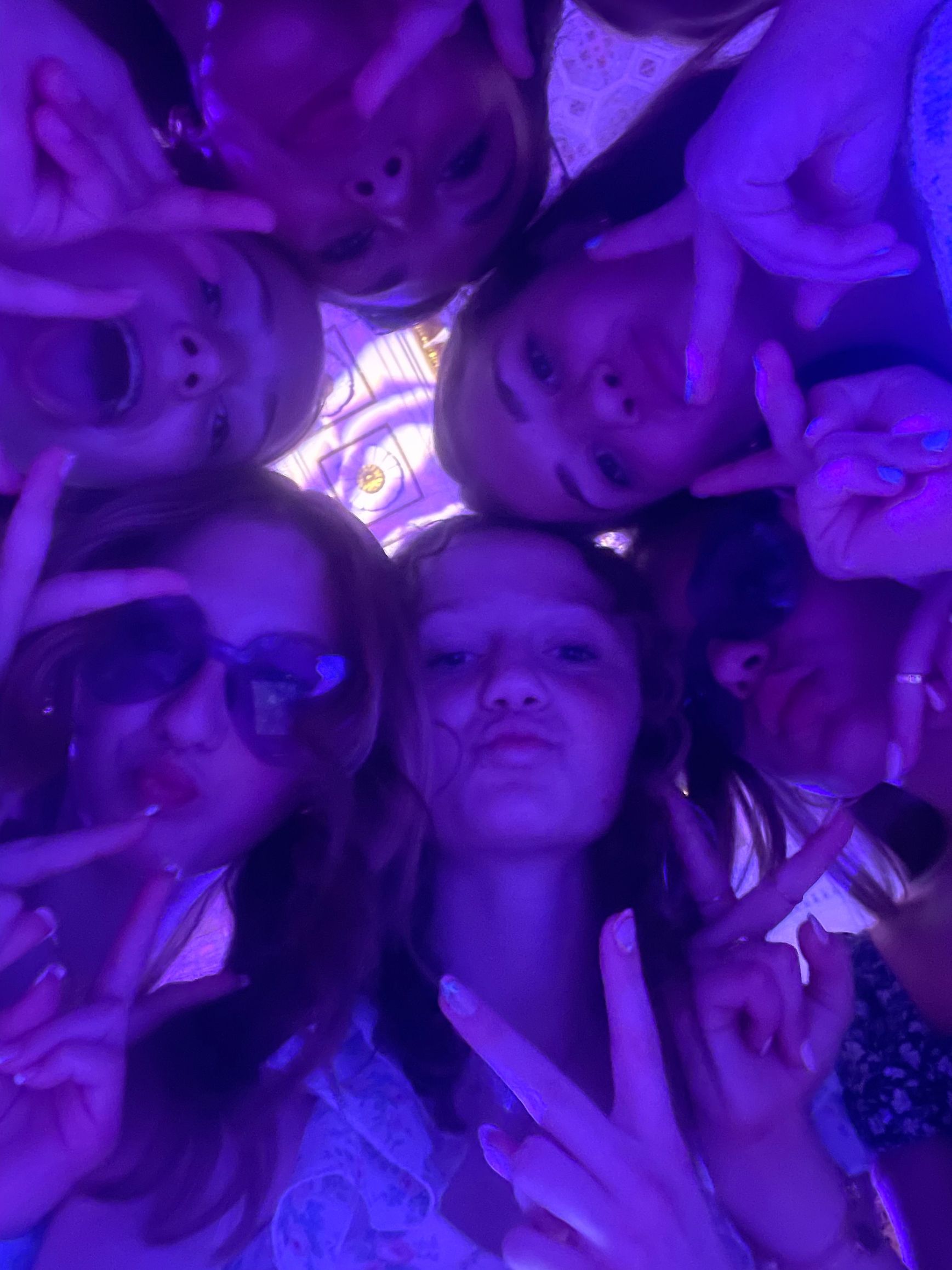 Group of young people with a purple hue, making peace signs and silly faces.