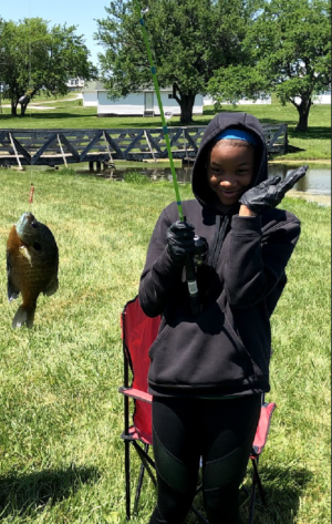 A young girl is holding a fishing rod in a field.