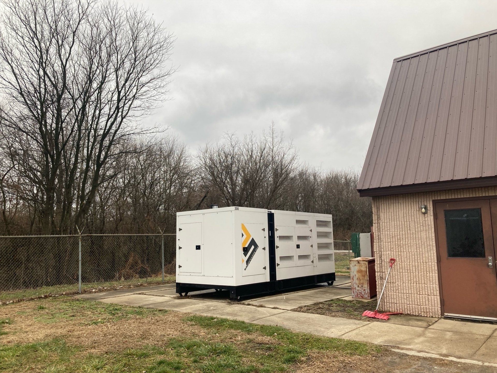 A large white generator is parked in front of a building.