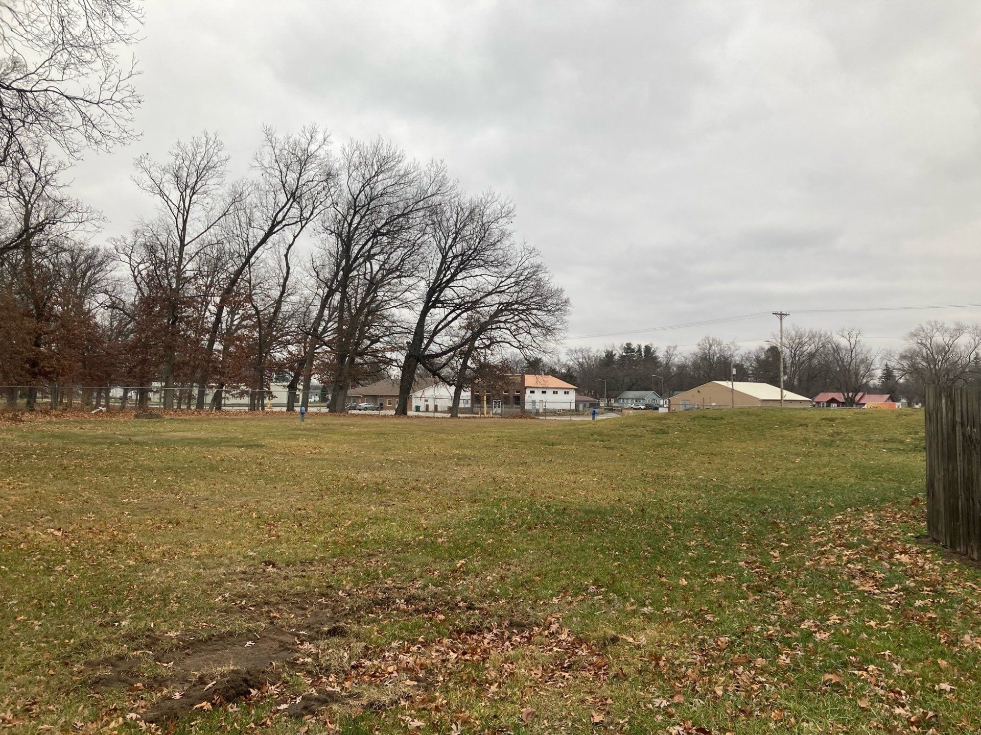 A large grassy field with trees in the background and a fence in the foreground.