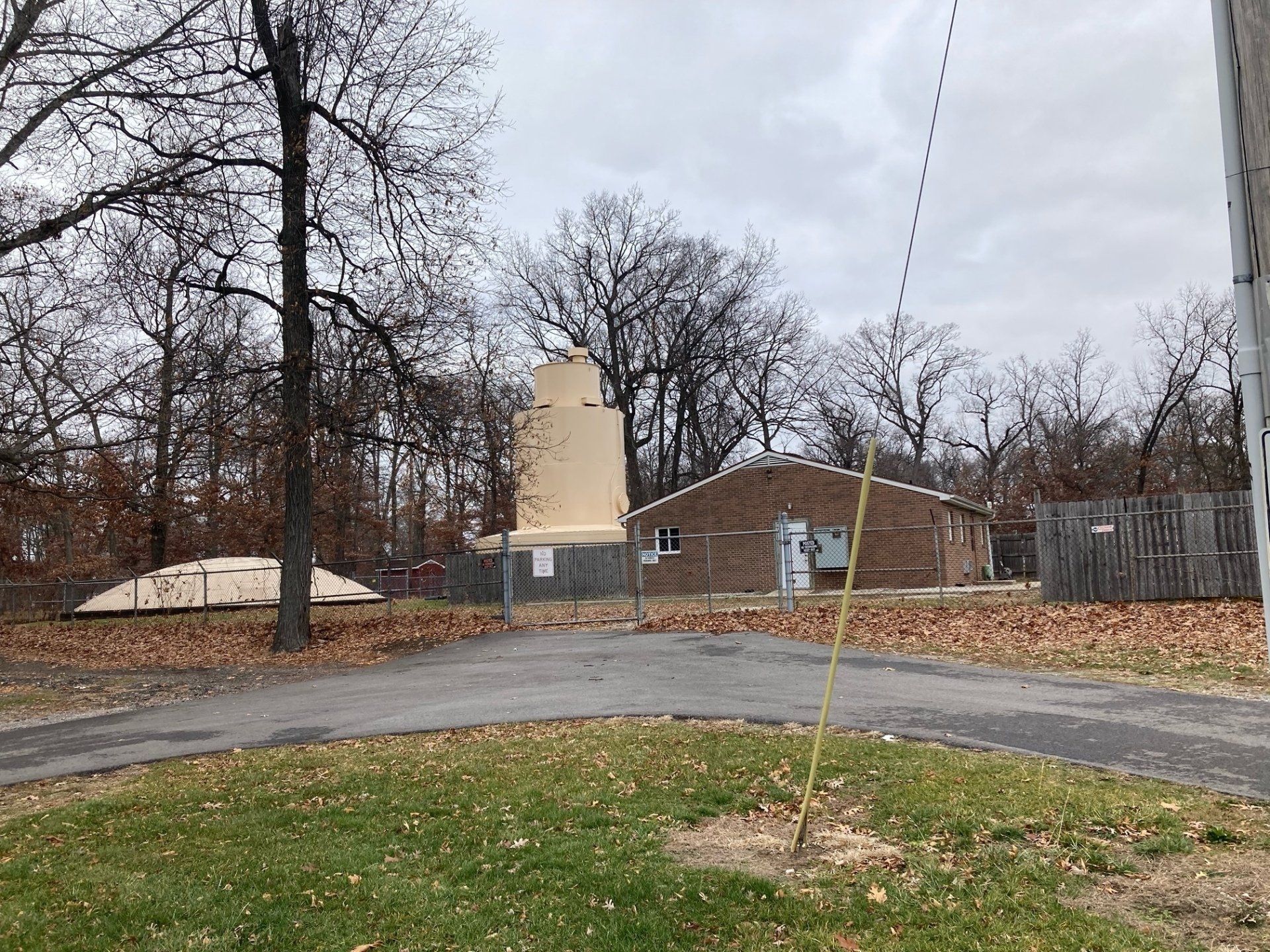 A brick building with a water tower in the background is surrounded by trees and grass.