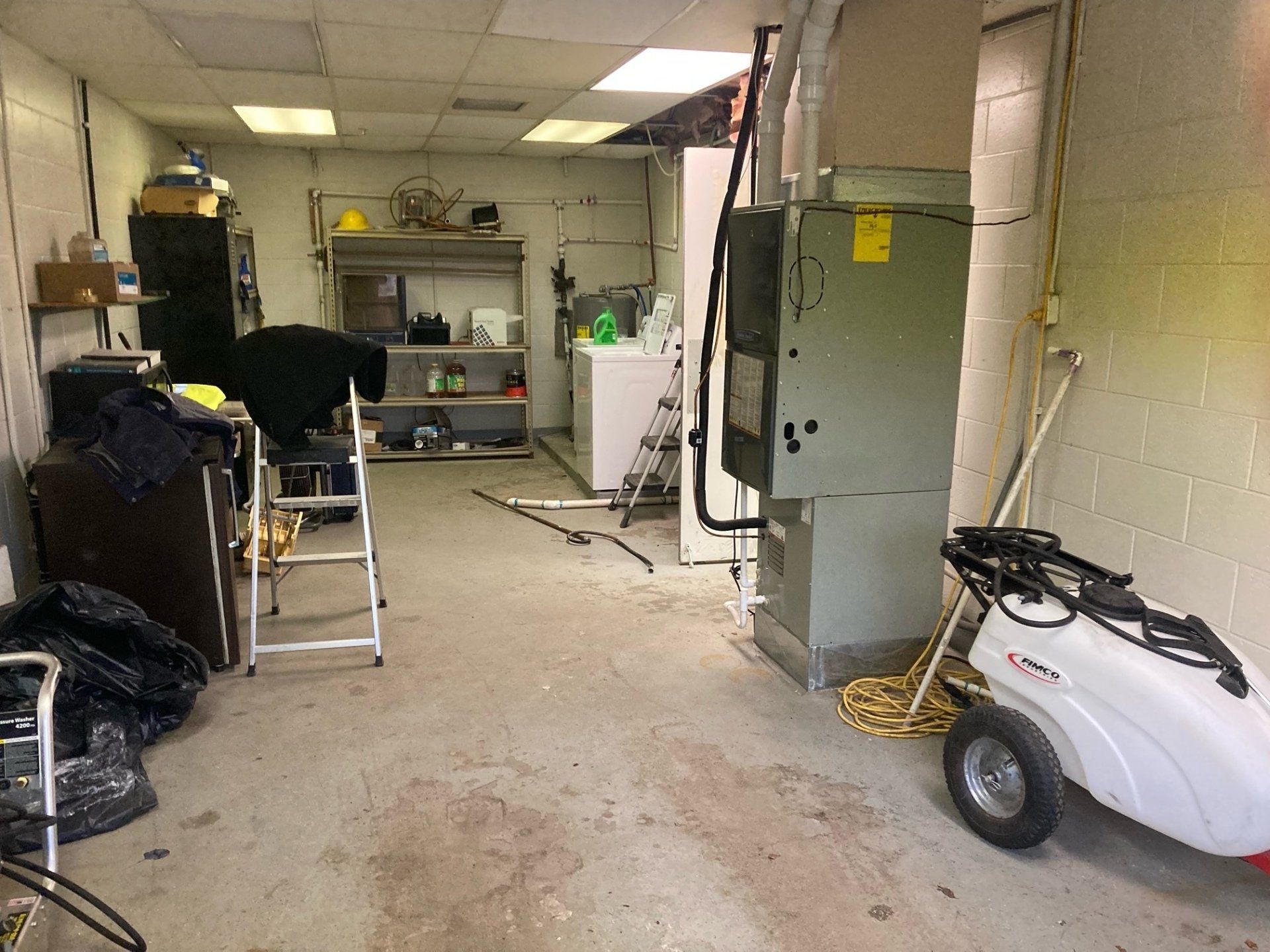 A dirty room with a ladder and a wheelbarrow in it