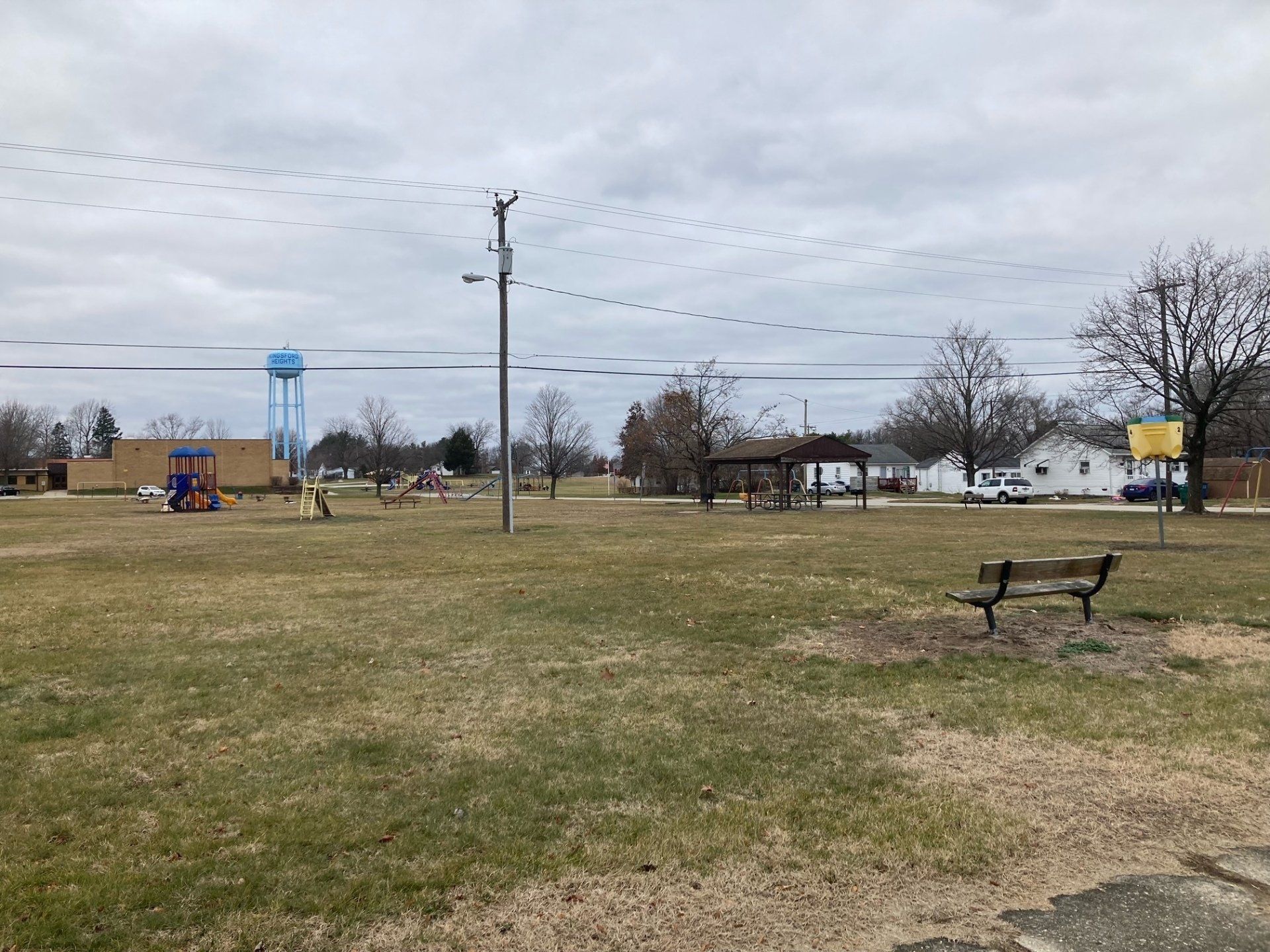 A park with a bench in the middle of it and a water tower in the background.
