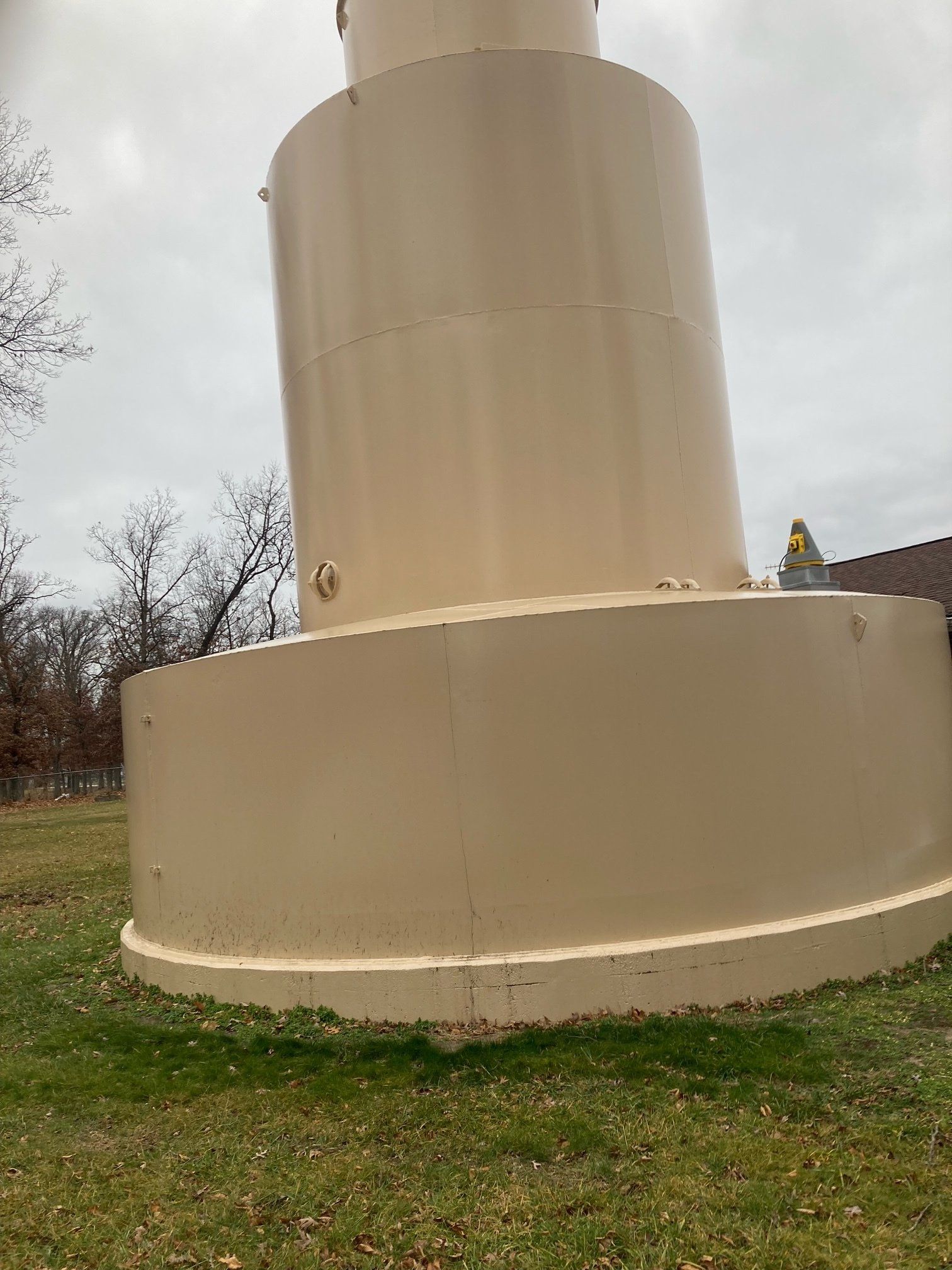 A large white tower is sitting in the middle of a grassy field.