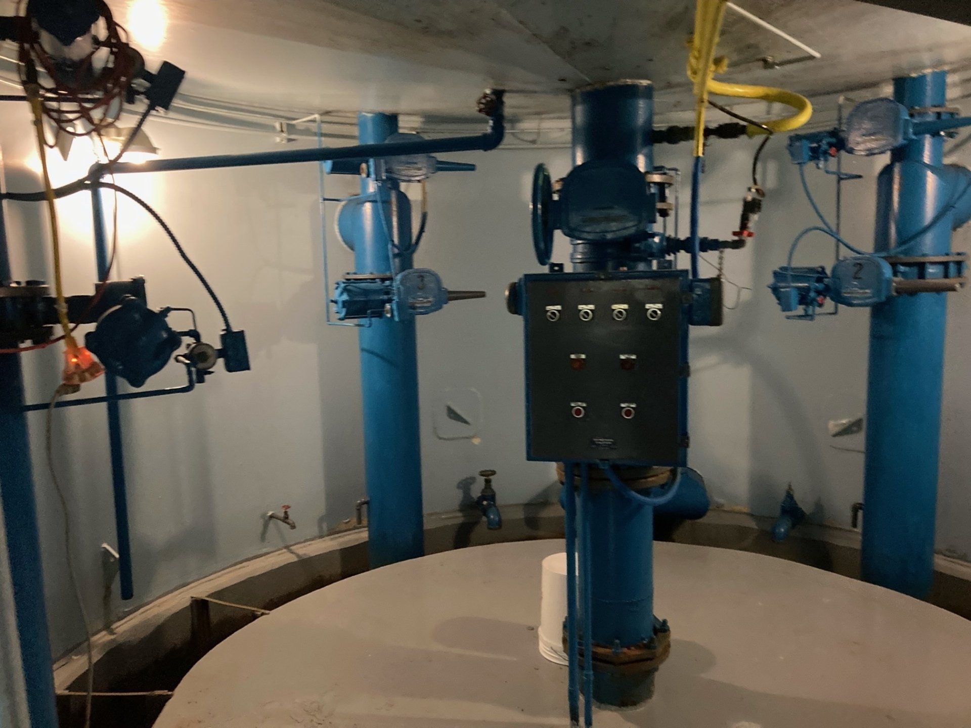 A room with a lot of blue pipes and a control panel