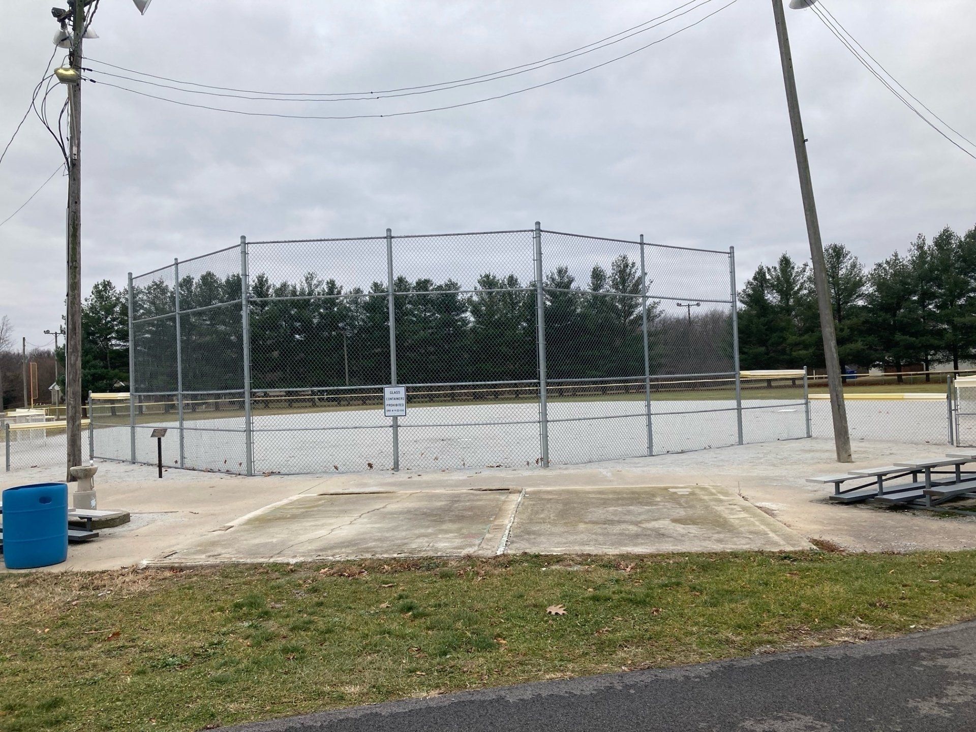 A basketball court with a fence around it in a park.