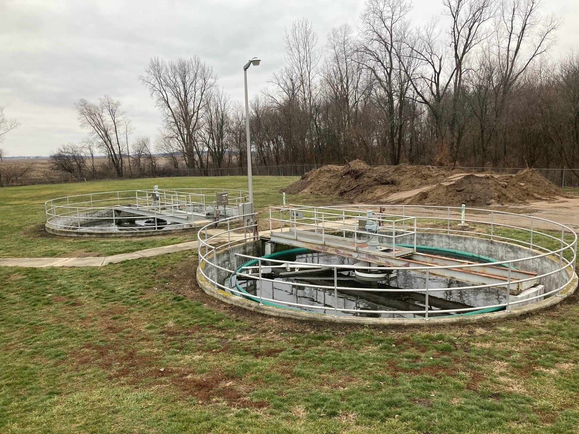 A group of circular tanks sitting on top of a lush green field.