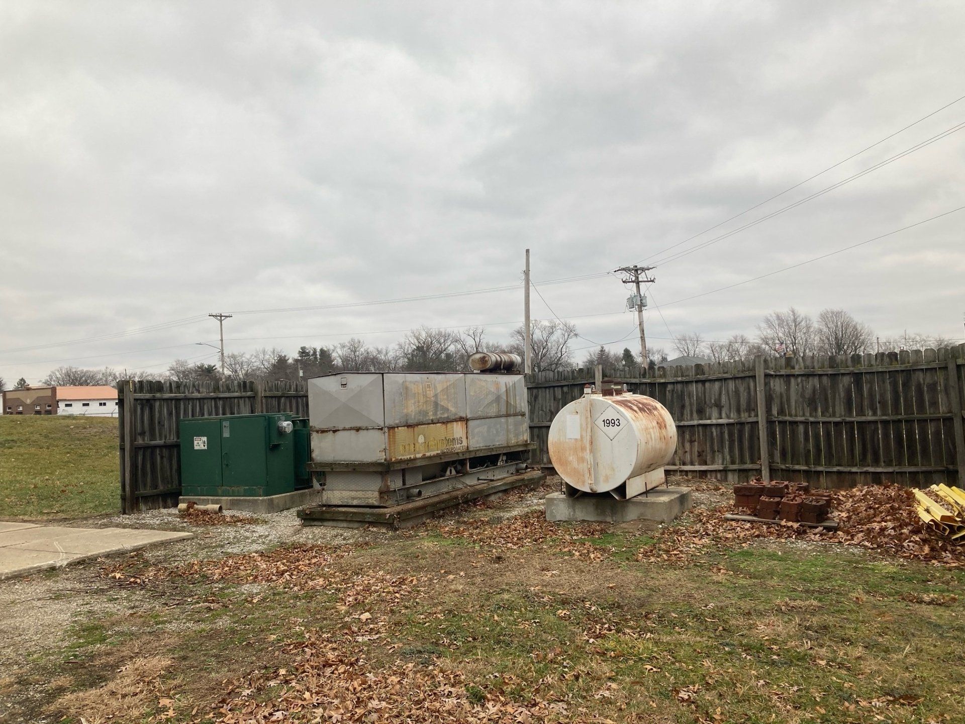 A large tank is sitting in the middle of a field next to a fence.