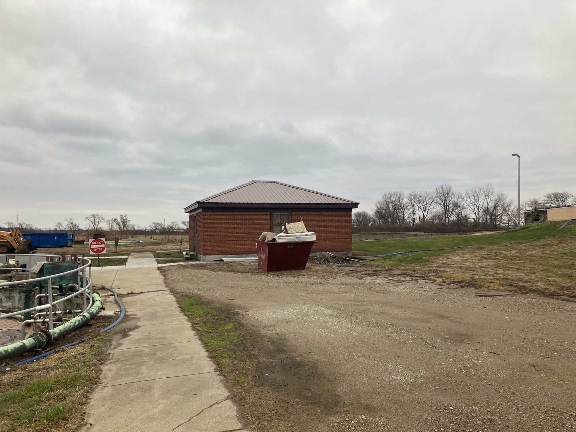 A small brick building is sitting in the middle of a dirt field.