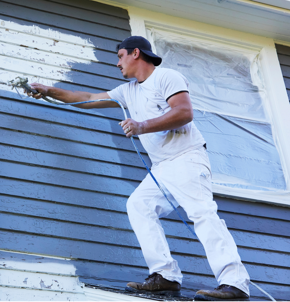 Man Using a spray gun on home exterior in COllege Statin, Texas