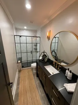A bathroom with a sink , toilet , shower and mirror.
