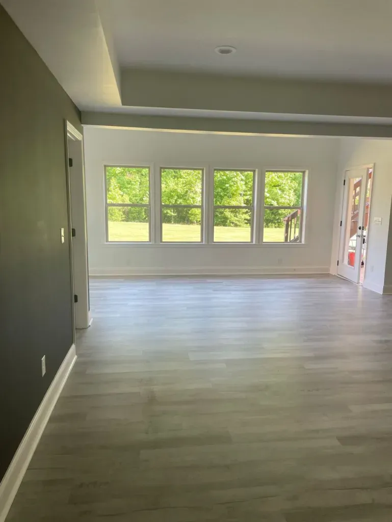 An empty living room with hardwood floors and lots of windows.