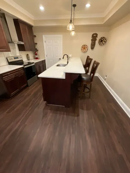 A kitchen with a large island , sink , stove and chairs.
