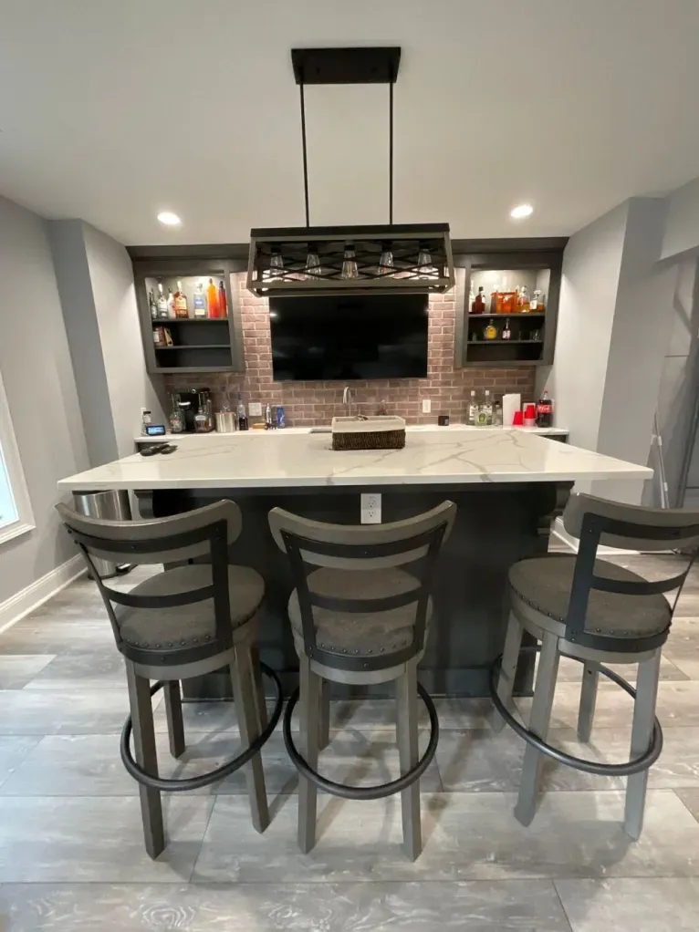 A kitchen with a bar and chairs and a flat screen tv on the wall.