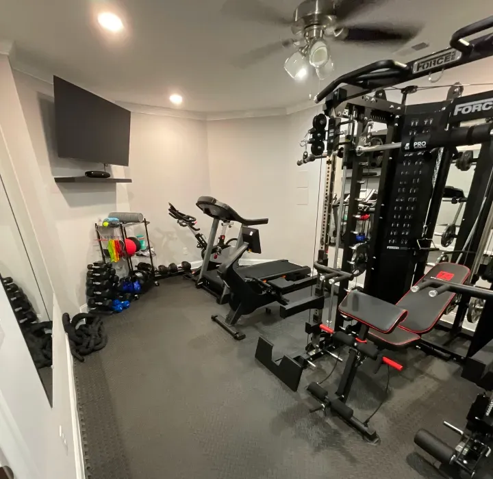 A gym with a ceiling fan and a tv on the wall