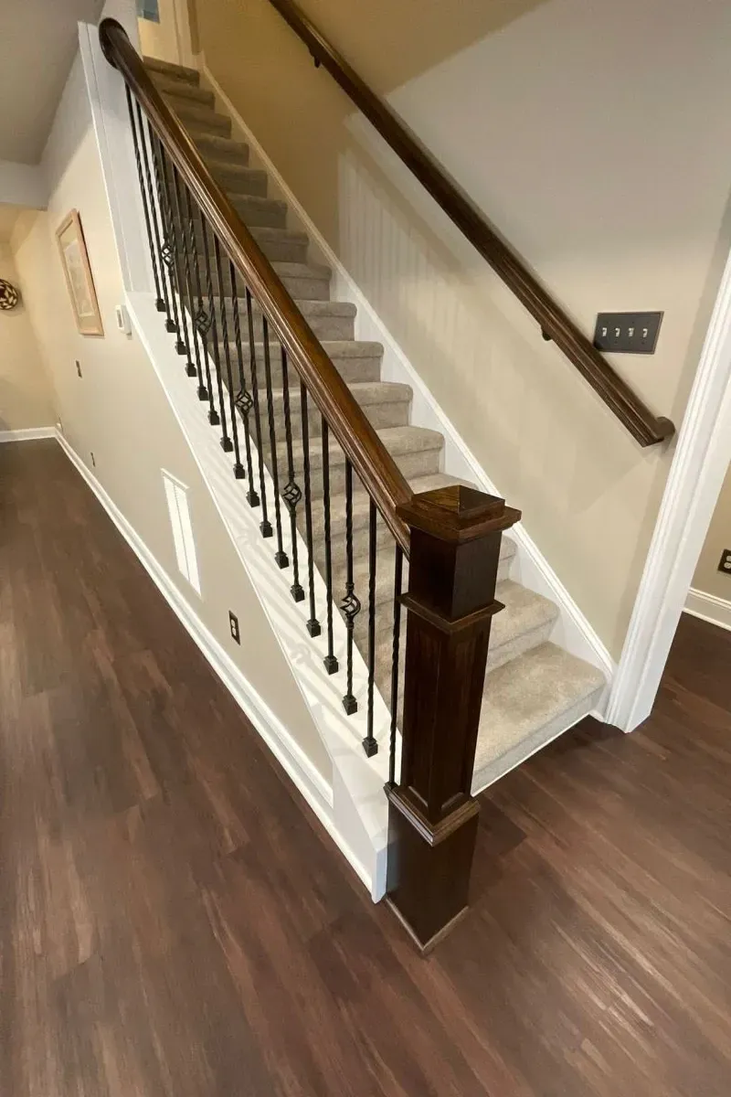 A staircase with a wooden railing and carpeted steps in a house.