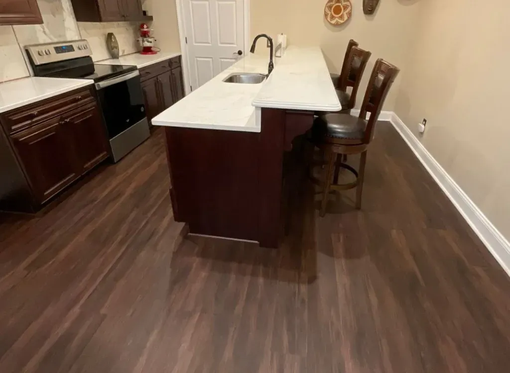 A kitchen with a large island , sink , stove and chairs.