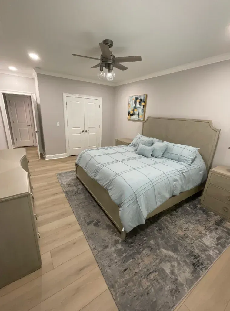 A bedroom with a large bed and a ceiling fan.