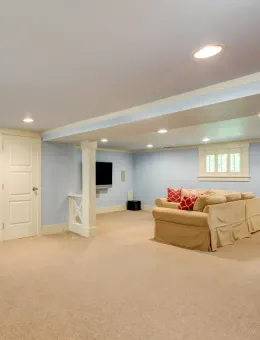 A living room in a basement with a couch and a television.