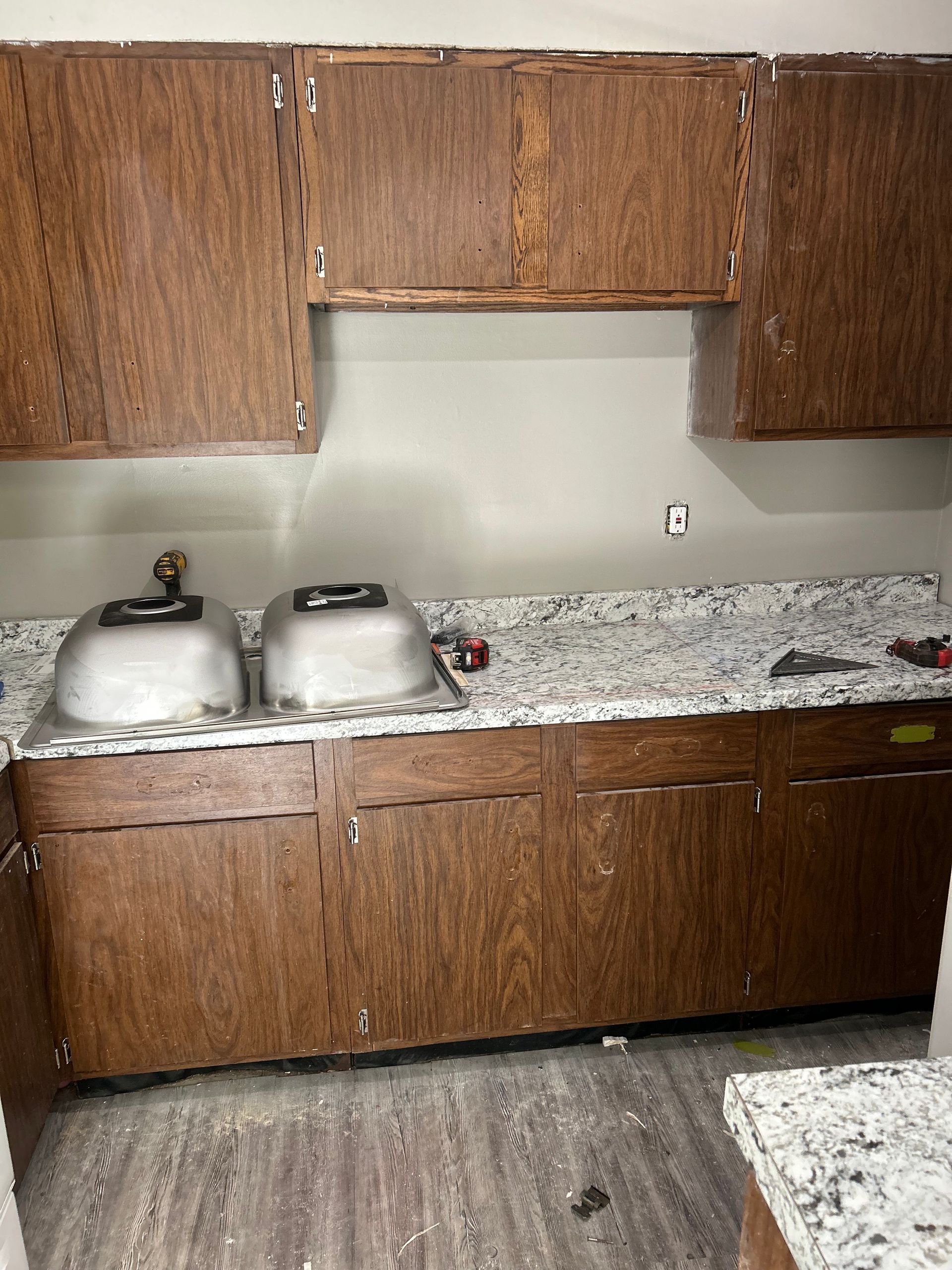 Kitchen with dark wood cabinets, a light gray countertop, and two stainless steel sinks.