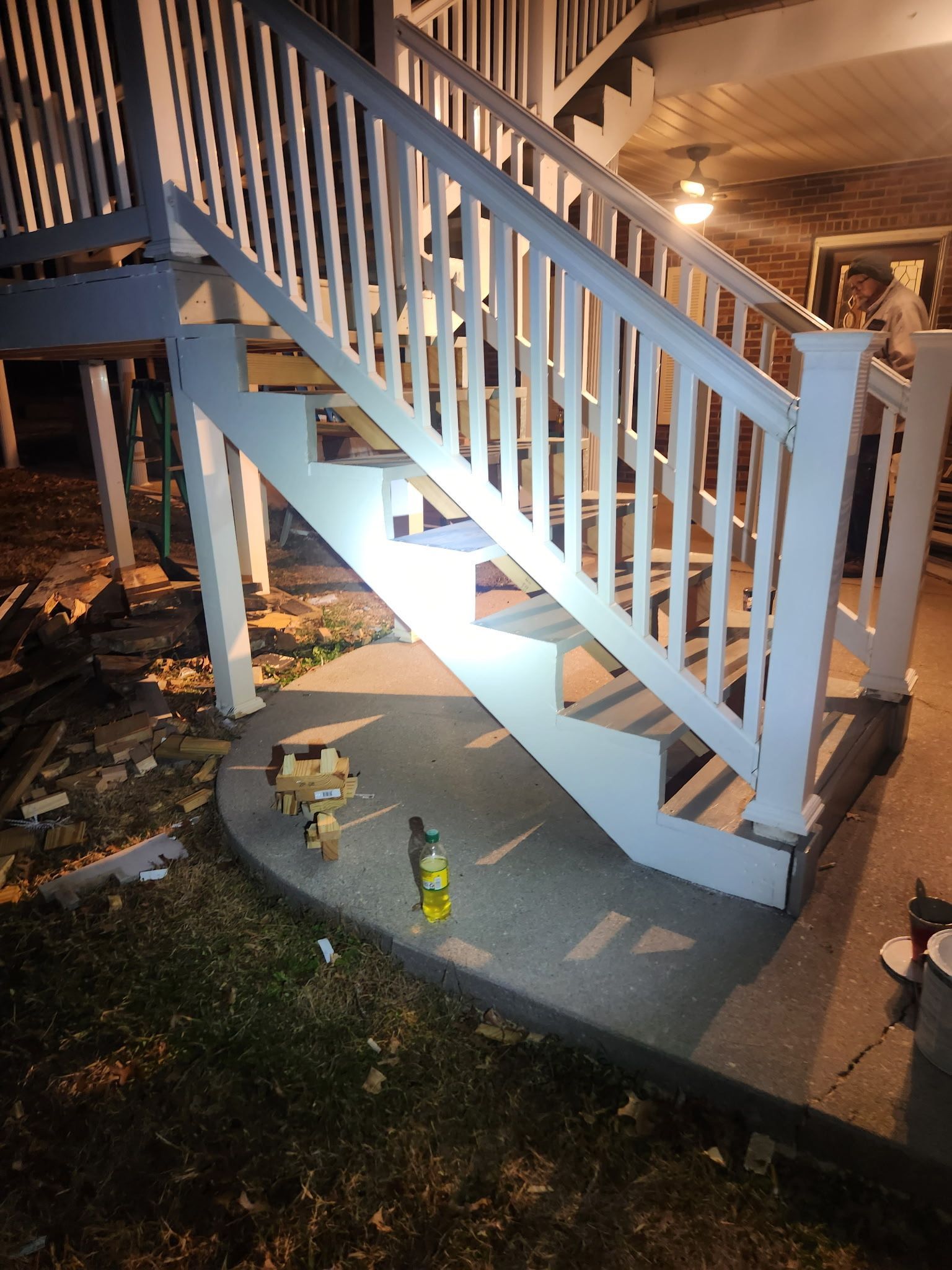 White painted wooden stairs leading up, over a concrete landing. A person stands nearby.