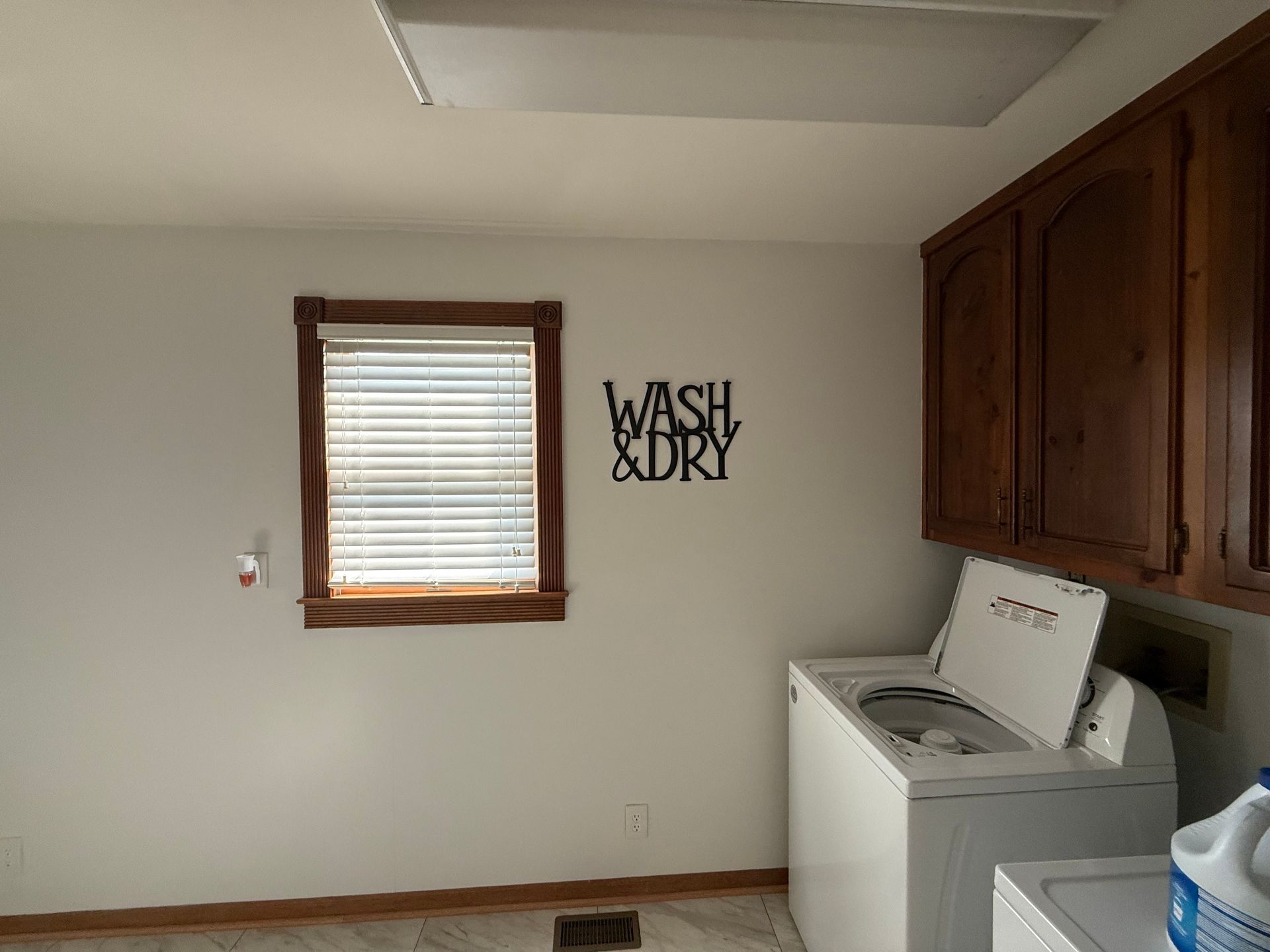 Laundry room with washing machine, cabinets, window, and 