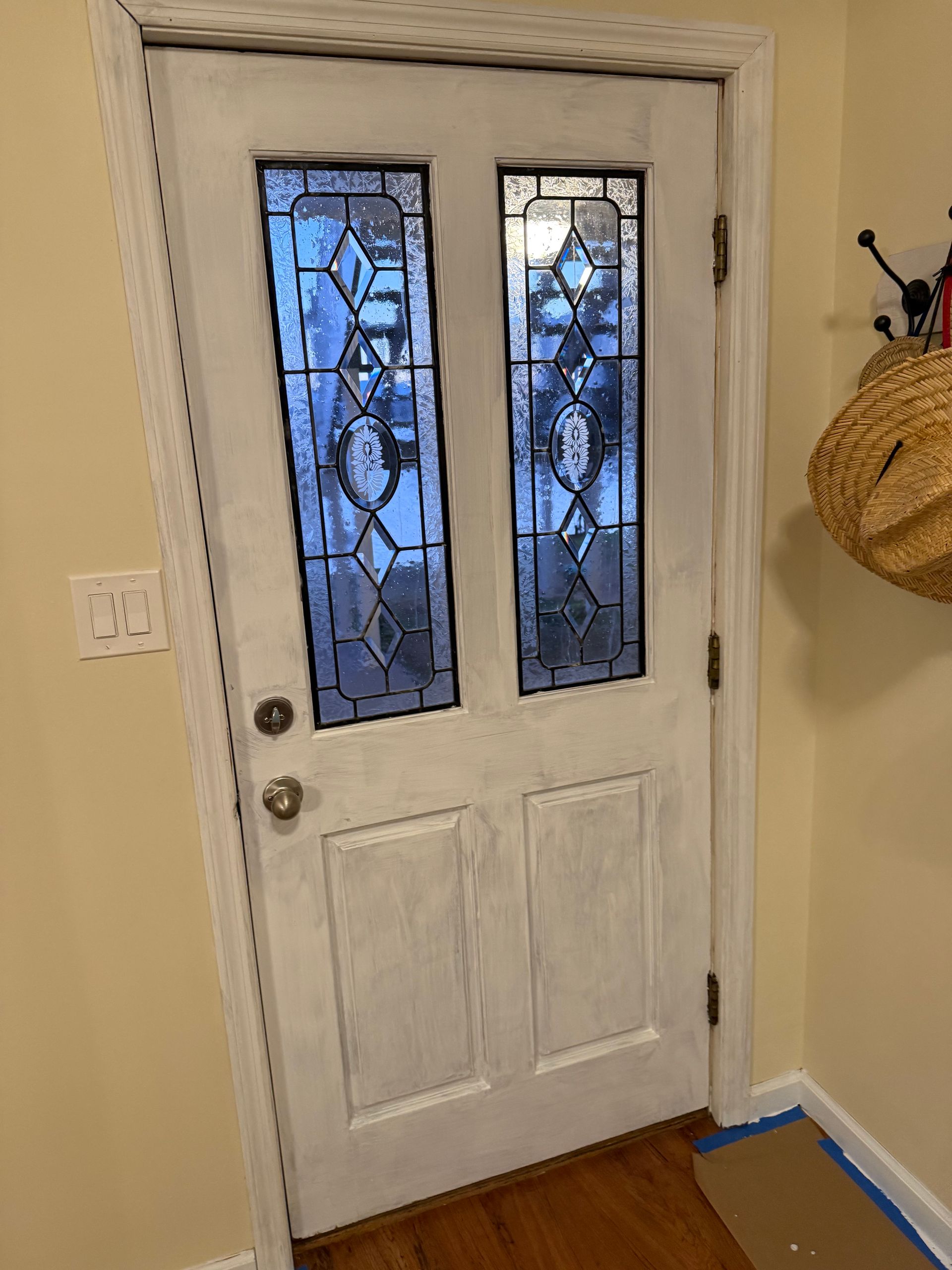 White painted front door with stained glass windows and a doorknob.