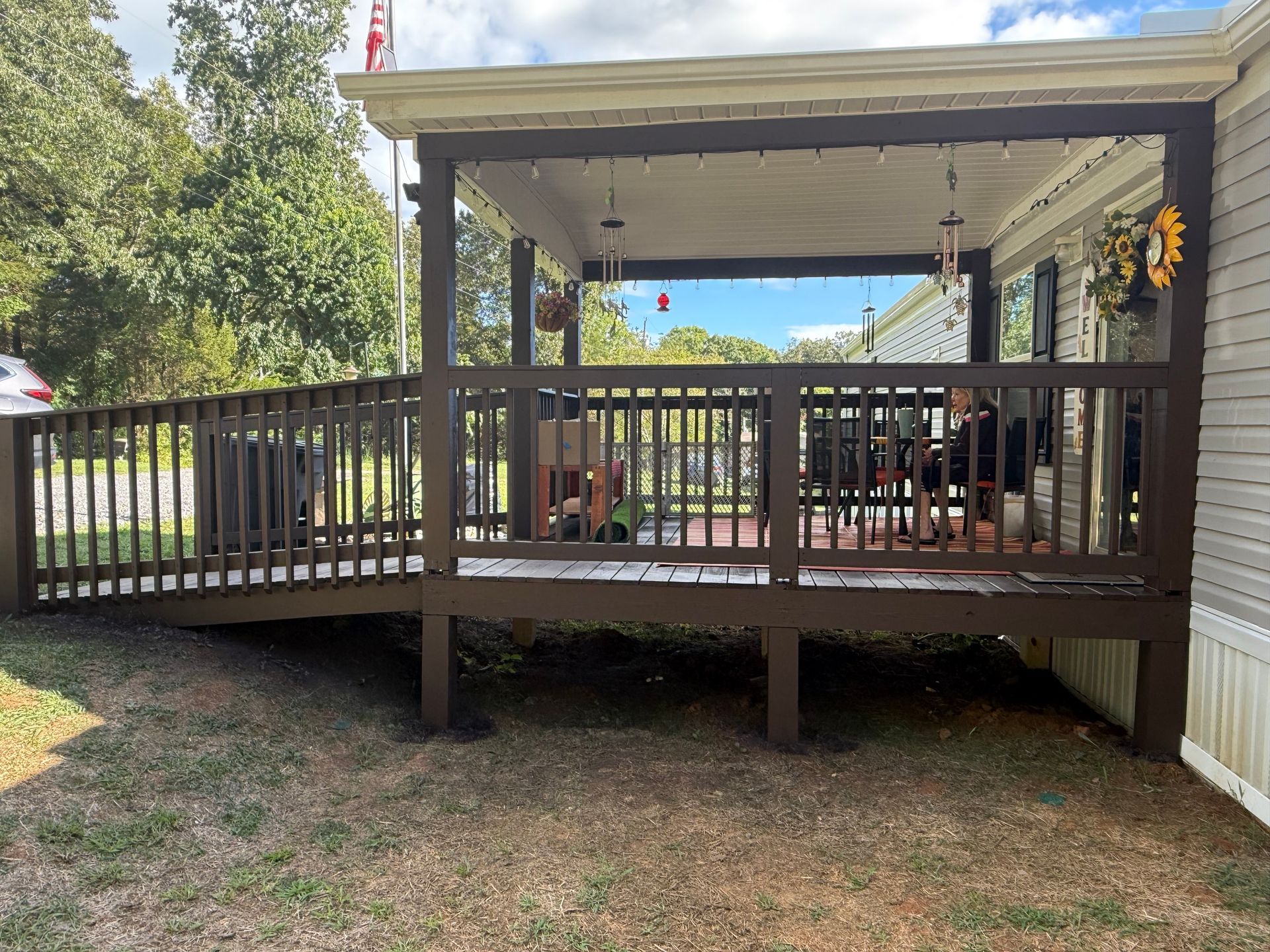 Brown wooden deck with ramp, covered porch, and decorations.