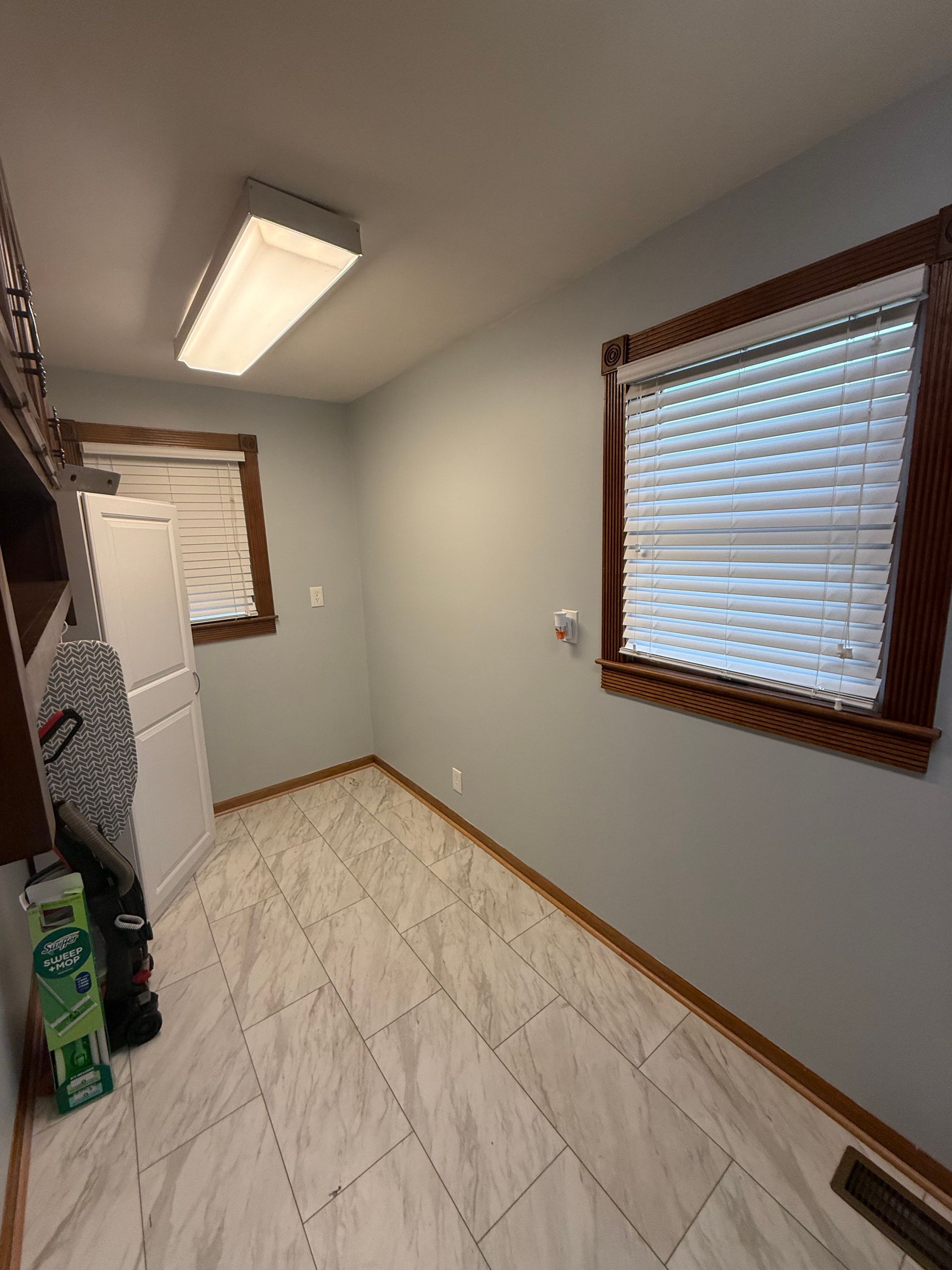 Laundry room with gray walls, white tile floor, and a white cabinet.