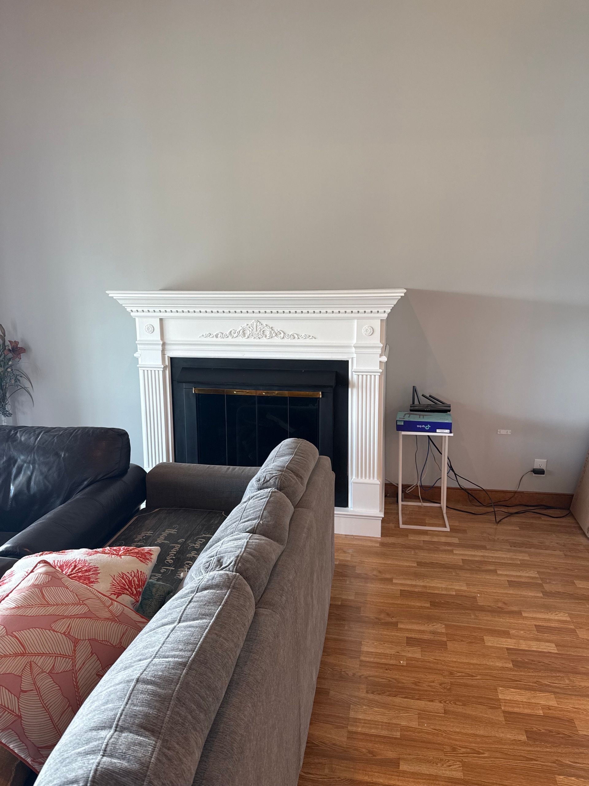 Living room with a white fireplace, gray couch, and hardwood floors.
